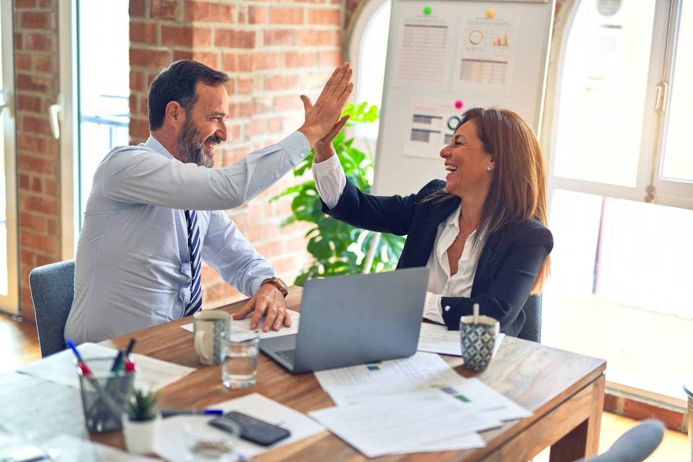 Two professionals celebrating good results at a desk